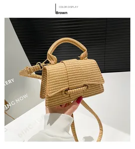 Detail of brown woven straw handbag with top handle and detachable shoulder strap