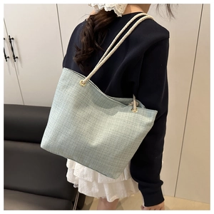 Détail du sac cabas tissé vert clair avec des poignées en corde de coton blanc et œillets