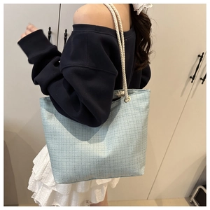 Détail d'un sac cabas tissé bleu clair avec anses en corde de coton blanc et texture