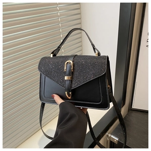 Dettaglio della borsa in pelle nera con patta glitterata e fibbia metallica dorata