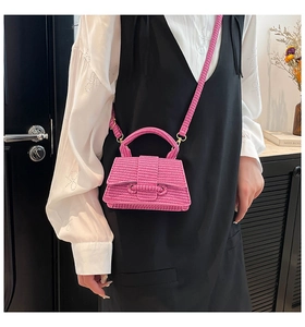 Detailed texture of bright pink woven hourglass handbag with gold hardware and strap