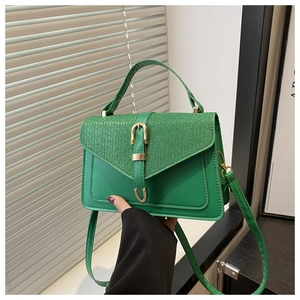 Dettaglio della borsa in pelle PU verde con pannelli in tessuto glitter e fibbia a U d'oro