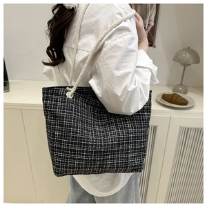 Détail du sac cabas en tweed à carreaux noir et blanc avec anse en corde sur l'épaule du modèle