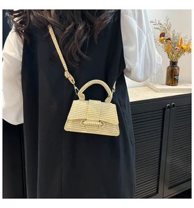 Close-up of the beige straw handbag with a unique hourglass shape and woven textures
