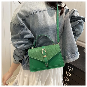 Dettaglio borsa a tracolla verde minimalista con patta glitterata e chiusura dorata