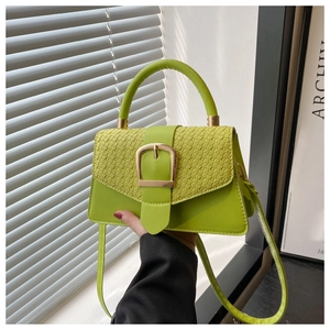 Detail of neon green textured handbag featuring golden buckle and top handle