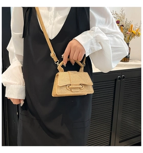 Close-up of minimalist straw woven hourglass handbag with adjustable strap in a lifestyle setting