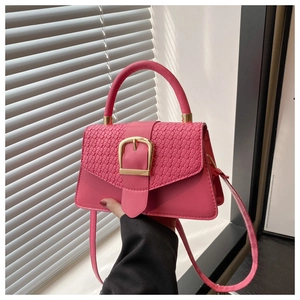 Detail of pink crossbody bag with woven texture flap and bold gold metal buckle