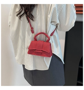 Detail of red woven texture hourglass crossbody bag with adjustable strap and top handle
