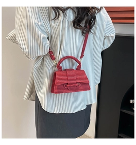 Detail of red woven texture hourglass bag worn as a stylish crossbody on a model