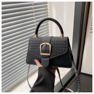 Detail of black woven leather handbag with a bold gold square buckle and sturdy handle