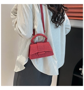 Close-up of a red woven hourglass handbag with curved base and elegant top handle