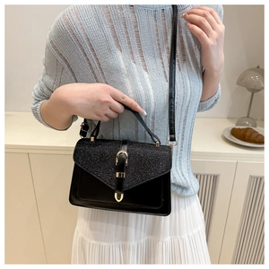 Detail of elegant black bag with glitter flap and gold clasp in minimalist interior