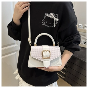 Detail of white mini crossbody bag featuring woven texture flap and gold square buckle