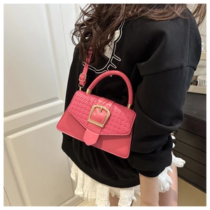 Detail of fuchsia crossbody bag with woven texture flap and gold metal buckle