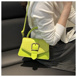 Close-up of vibrant neon green crocodile-patterned bag with elegant gold buckle