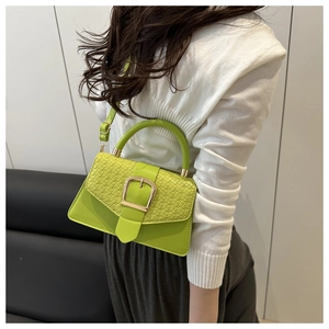 Detail of lime green crossbody bag with textured flap and large gold buckle closure