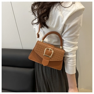 Detail of caramel brown crossbody bag with woven texture and gold square buckle