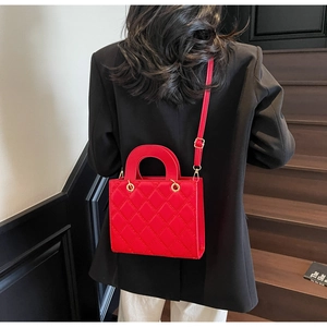 Dettaglio di una borsa trapuntata rossa con finiture dorate su una modella di stile