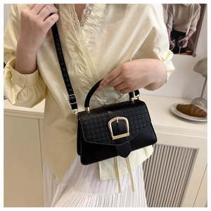 Detail of black square bag featuring woven texture flap and large gold U-shaped buckle