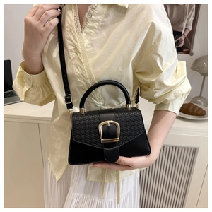Detail of a black square crossbody bag with woven texture flap and golden buckle
