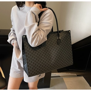 Detail of retro monogram tote bag with grey M patterns and elegant gold hardware accents