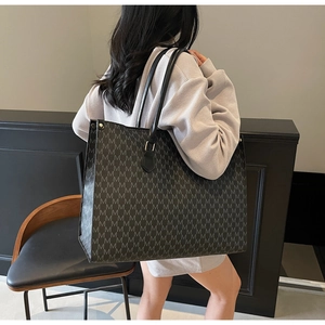 Detail of a black and grey patterned tote bag worn by a model in a minimalist setting