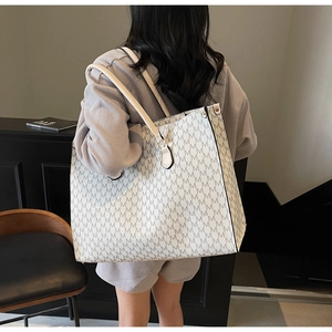 Detail of the large tote bag showing refined M-letter print and gold rivet hardware
