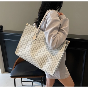 Detail of a large tote bag with M-pattern print and premium leather handles
