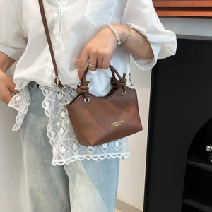 Brown bucket bag with knot handle detail and adjustable strap for daily commute