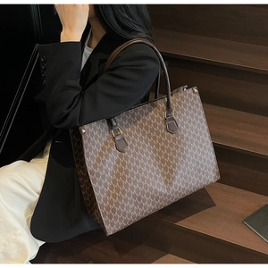 Detail of vintage monogram tote bag with brown leather handles and golden rivets