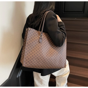 Detail of vintage brown leather tote bag with M-letter pattern and long handles