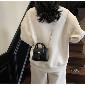Détail du mini sac carré noir minimaliste avec chaîne argentée et boucle à ardillon