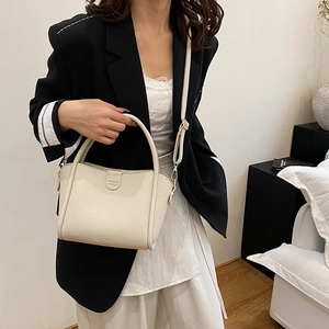 Elegant cream lychee leather bucket bag with top handles and adjustable shoulder strap