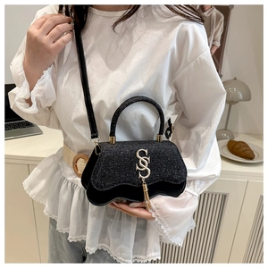 Detail of black sequined crossbody bag featuring a silver SS logo and metal tassel