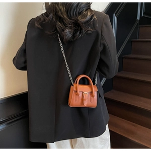 Back view of a woman wearing a mini brown faux leather crossbody bag with silver chain