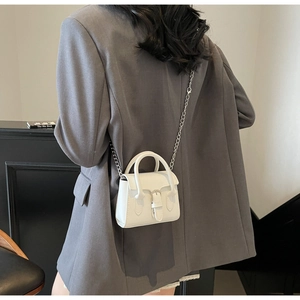 Vue latérale du mini sac blanc avec chaîne argentée porté sur une veste grise chic