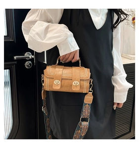 Detailed shot of brown cylinder Boston bag with pearl trim and ethnic woven strap