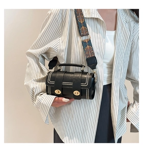 Detail of black Boston bag with white studs and ethnic style wide detachable shoulder strap