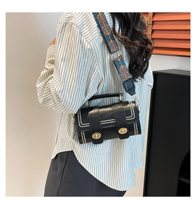 Detail of black crossbody bag with gold locks and colorful ethnic woven wide strap