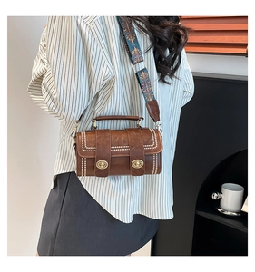 Detailed view of brown crossbody bag with rivet trim and bohemian embroidery strap