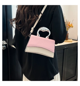 Detail of pink and white crossbody bag with unique silver metallic handle worn by model