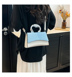 Detail view of the French style square bag showing blue leather and silver metal handle