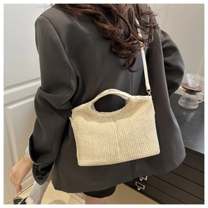 Back view of a woman wearing the woven straw handbag with an adjustable shoulder strap