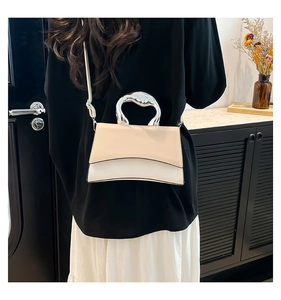 Detail of unique silver metal handle and two-tone beige leather crossbody bag