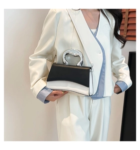 Detail of a black and white leather handbag with a silver fluid-shaped metal handle