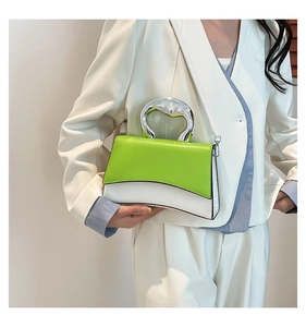 Close-up of a color-block bag with green and white panels and unique silver metal handle
