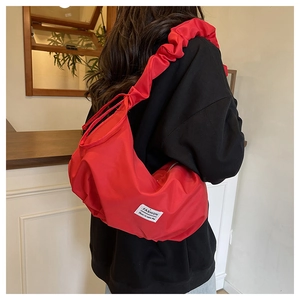 Detail of red ruched crescent bag with FASHION label on model shoulder in a cafe