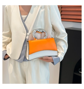 Detail of trendy orange and white patchwork handbag with curved silver metal handle and strap