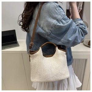 Detail of woven bucket bag featuring brown leather trim and detachable shoulder strap